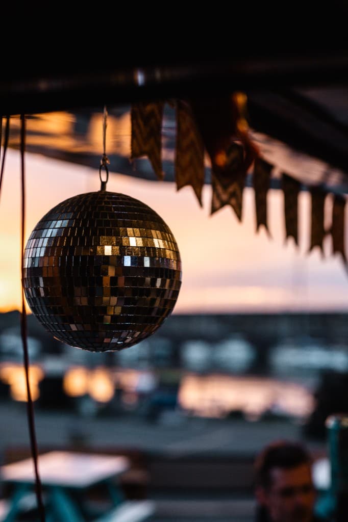A mirror ball catching the sunset over Dunbar harbour at Nauti, with bunting and the marina behind.