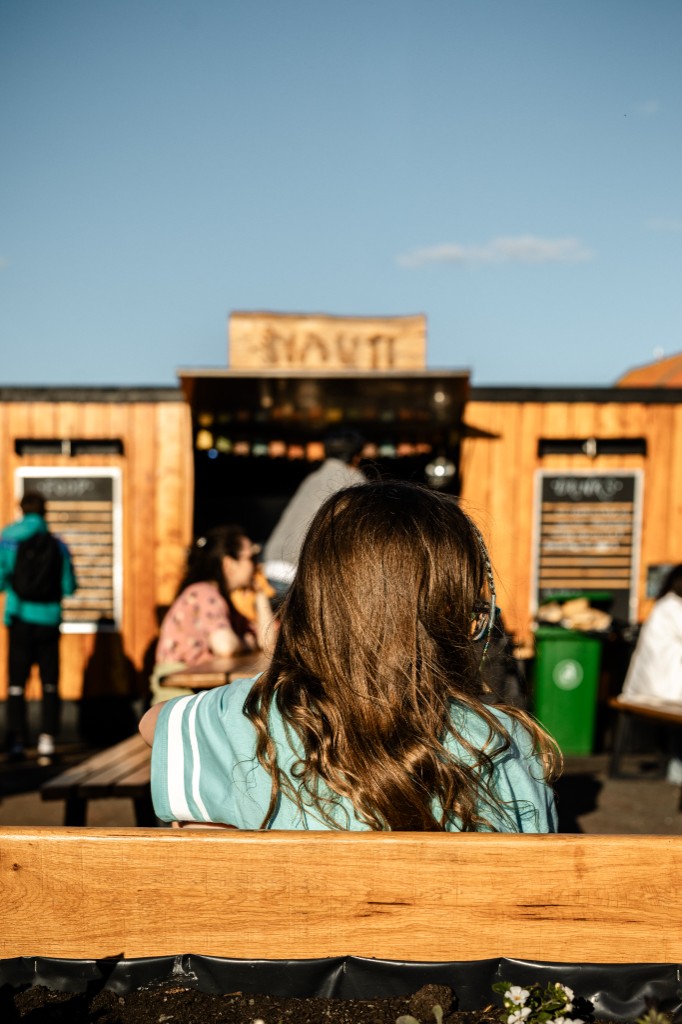 The wooden Nauti seafood shack at Dunbar harbour with its menu boards and carved sign, customers seated at picnic benches in the sun.