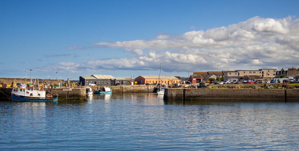 Port Seton harbour with fishing boats moored between the stone harbour walls