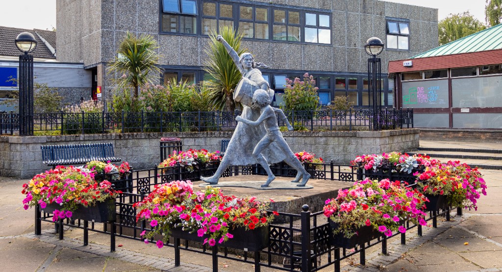 Statue of a woman and child among flower beds in Tranent civic square